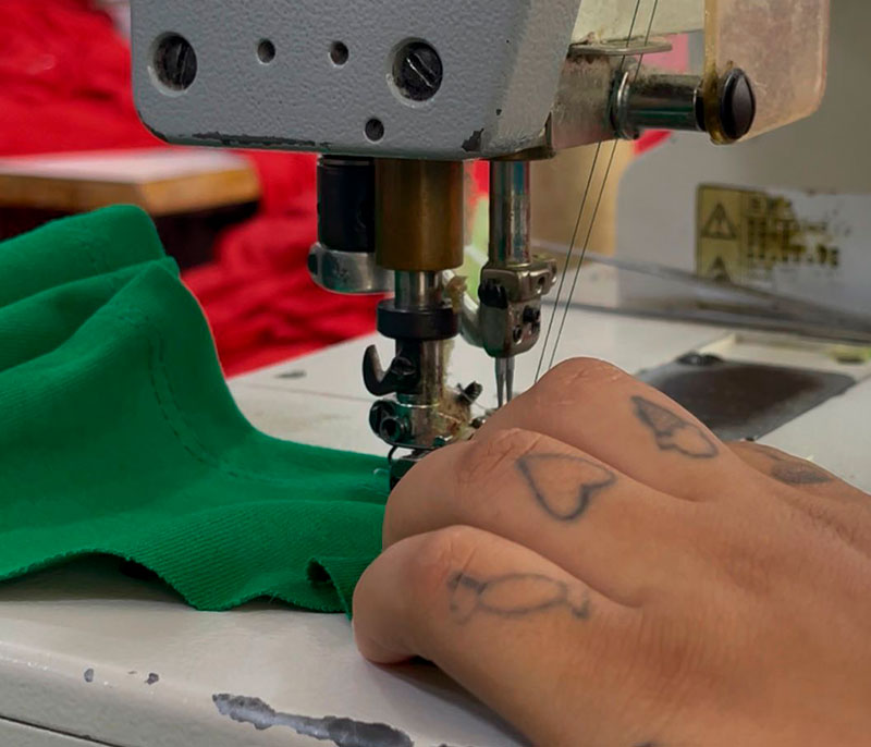 Manos cosiendo en taller de confección de la Fundación, Centro El Buen Pastor